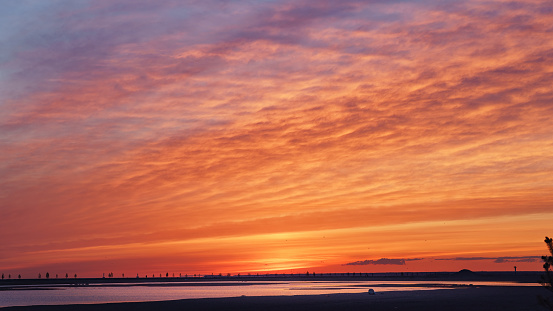 Bright red and orange sunset sky over the empty sea coast