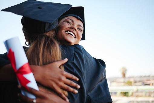 Students, graduation and happy together for hug to celebrate at college. Women, friends and graduate with certificate for study with success in education, learning and goal achievement at university