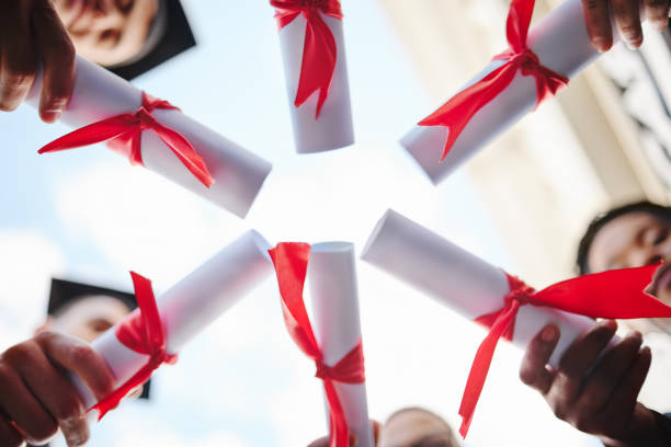 Graduation circle, success and students certificate, diploma or degree in hands huddle from below. Low angle, education and university people, friends or graduates celebrate after studying in academy