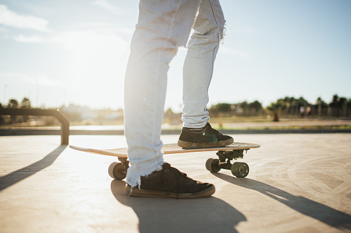 Back lit shot of skater's feet on skateboard. He is about to start to ride