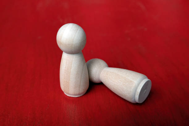 istock two wooden figures on red background. one standing and one lying down, 1444253004