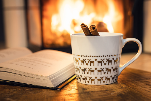 istock Coffee cup and book in front of fireplace 1444255886