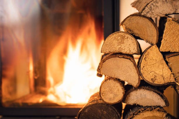 firewood stack in front of stove. - şömine stok fotoğraflar ve resimler