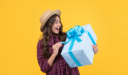 surprised teen girl with present box on yellow background.