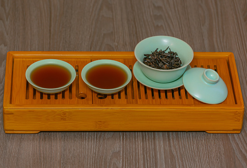 Cups, chaban selective focus. Gongfu cha tea ceremony. Zhu-yao Chinese ceramics on a bamboo tea board. Brewing Chinese tea in ceramic dishes gaiwan, chahai, cups during the tea ceremony close-up.