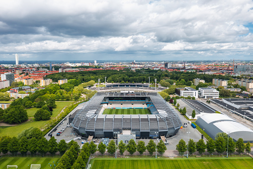 Malmö, Sweden - May 2022: Aerial summer view of Nya Malmö Stadion (Eleda Stadion), home stadium for football club Malmö FF (Malmö Fotbollförening). City skyline panorama in the background.