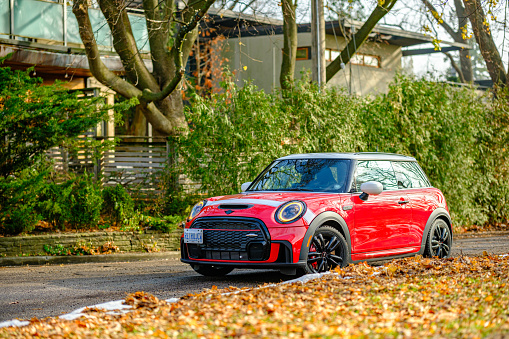 Toronto, Ontario, Canada- November 24, 2022. Morning image of Chili red colour MINI COOPER on the streets of Toronto East side, Canada. This is the third generation model F56 JCW, since BMW took over iconic brand of MINI. MINI featured in the photo is John Cooper Works model, the most powerful 2 door version. For the first time, this compact car features engine build and designed by BMW, and packs even more power and torque than previous models since 2002 to present. Original design clues and themes are still present on this brand new model. Mini has been around since 1959 and has been owned and issued by various car manufacturers.