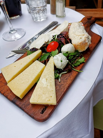 A board of various cheeses arranged on a wooden board as a wine snack
