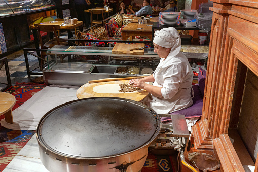 Istanbul, Turkey - May 19, 2022: An elderly woman makes pancakes in the center of Istanbul
