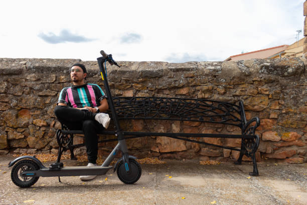 istock man sitting on a bench taking a selfie with his electric scooter 1444273897