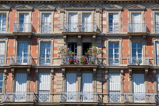 Old fashioned house with open windows and some flowers on the balcony
