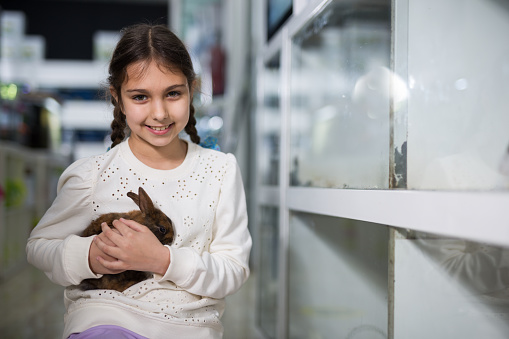 Portrait of Happy little girl shopper looking for bunny in pet store