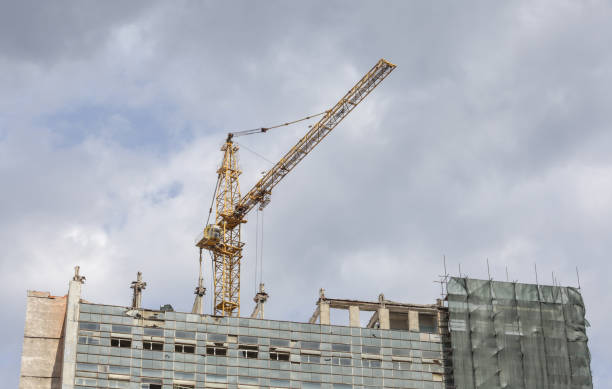 istock A construction crane and a building under construction against a blue sky background. A construction crane is working, the walls of buildings are being erected. 1444277034