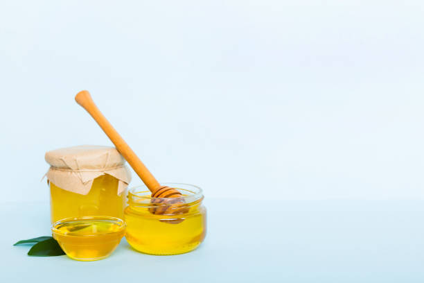 istock Honey in jar with leaves and honey dipper on colored background top view with copy text 1444277799