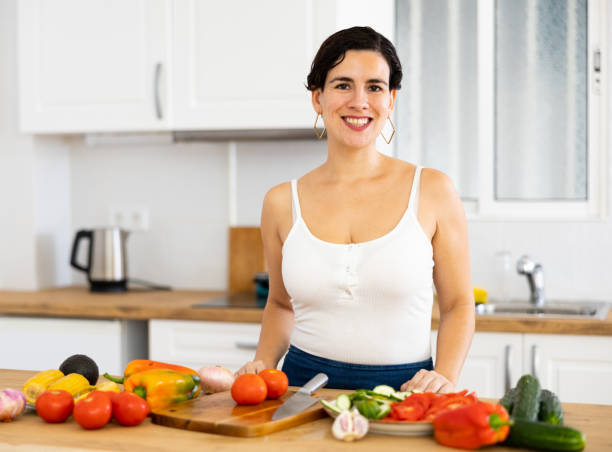 istock Smiling young Hispanic woman preparing salad in home kitchen 1444278633