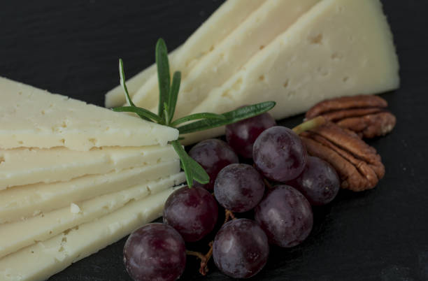 Assorted cheeses with grapes, nuts, Goat cheese. wooden board