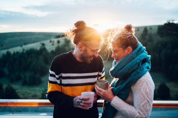 istock Young couple drinking coffee or tea while standing on their balcony at sunrise 1444281834