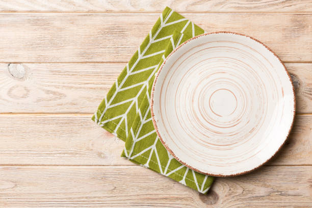 istock Top view on colored background empty round white plate on tablecloth for food. Empty dish on napkin with space for your design 1444283116
