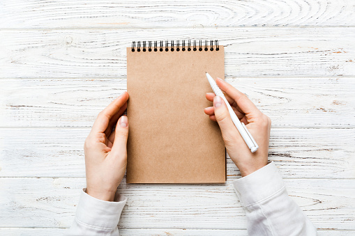 Woman hand with pencil writing on notebook. Woman working on office table. Female hand holding pencil and sketchbook. Mock-up Concept.