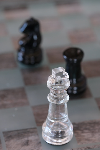 Glass chess pieces on chessboard.