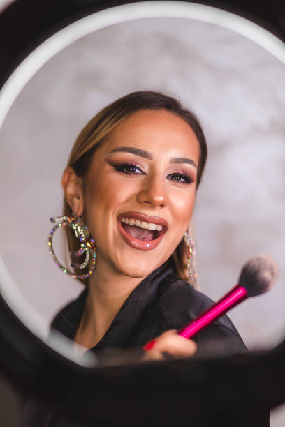 istock Beautiful young make-up artist posing with a make-up brush in front of a ring light 1444290375