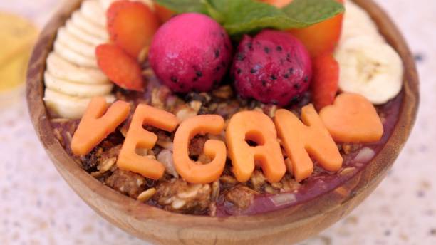 istock Plant-based breakfast concept. Dragon fruit smoothie with nuts, bananas, strawberries, served in a wooden bowl with large Vegan letters as decoration. 1444293801
