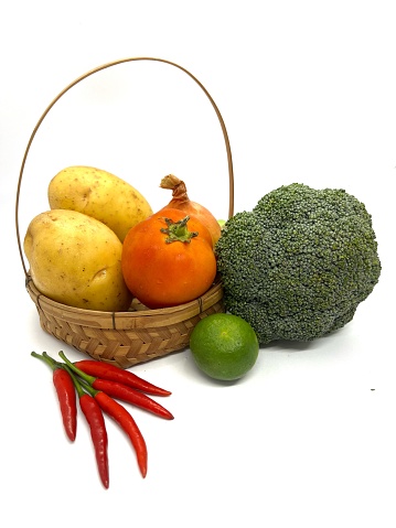 Vegetables in a basket with capsicum, tomato, potato, broccoli and lime.