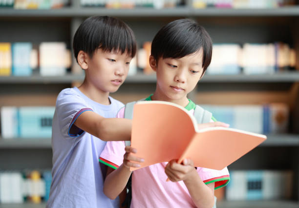 Happy Asian kid reading book in library