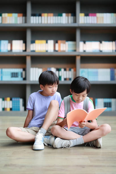 School children reading books in the library stock photo