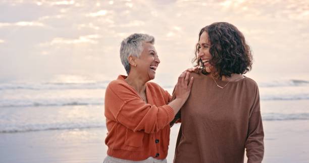 felicidad, amigos y mujeres mayores en la playa disfrutando de la naturaleza, el verano y el aire libre juntos. amor, amistad y mejores amigos ancianos riendo, sonriendo y uniéndose junto al océano en vacaciones de jubilación - happy time fotografías e imágenes de stock