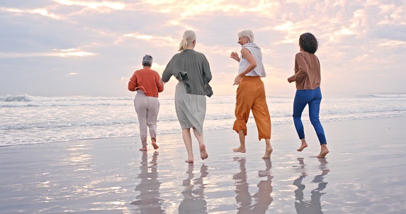 Beach, water and vacation with senior friends walking in the sea or ocean while having fun together. Sky, earth and nature with a mature female friend group enjoying summer while bonding in the water