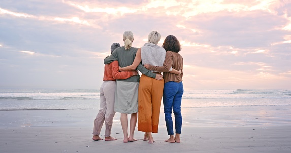 Friends, beach and back of senior women looking at sunset, waves and standing by ocean. Love, friendship and group of mature females enjoying holiday, summer vacation and weekend in retirement by sea
