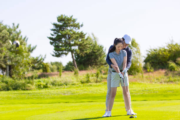 istock A young East Asian man and woman practicing golf on a sunny daytime golf course, coach and student - stock photo 1444320571