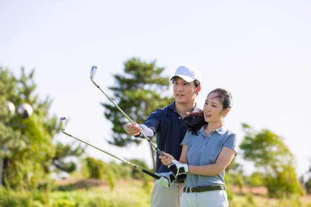 instruktor golfa i golfista, para ćwicząca golfa na zielonym polu golfowym w słonecznym świetle dziennym - zdjęcie stockowe - golf golf swing men professional sport zdjęcia i obrazy z banku zdjęć