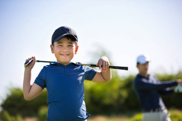 junger ostasiatischer junge beim golfen auf einem sonnigen tagesgolfplatz mit einem golfschläger auf schultern - archivfoto - sports venue clothing outdoors front view stock-fotos und bilder