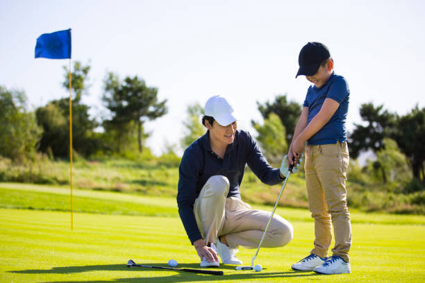 Father and son practicing hole-in-one golf or tee shots on a sunny golf course, coach and student, encouragement and praise - stock photo