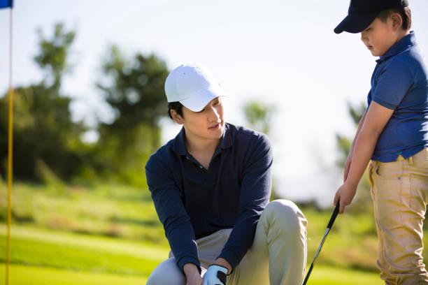 istock Father and son practicing hole-in-one golf or tee shots on a sunny golf course, coach and student, encouragement and praise - stock photo 1444321685