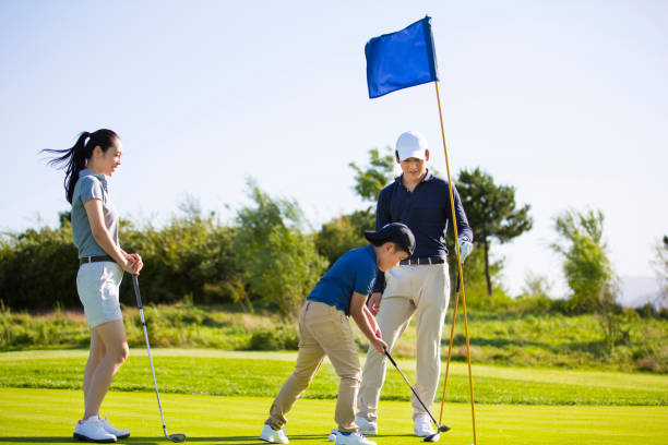 istock A young Toya family of three practicing on a sunny golf course, the son is doing the hole-in-one - stock photo 1444321920