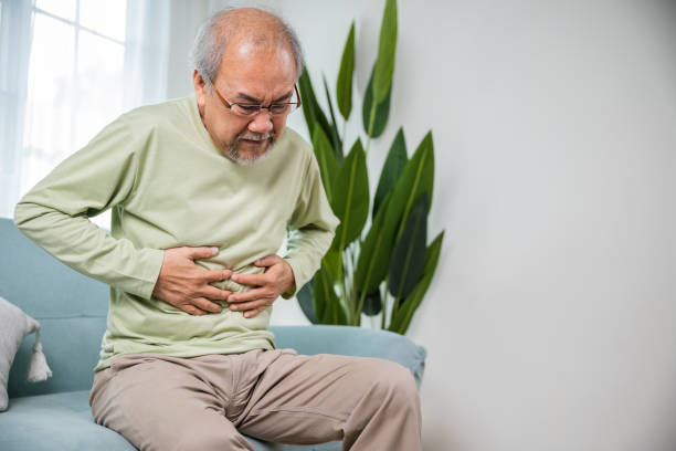 istock Elderly Asian old man sitting on sofa having stomachache 1444323219