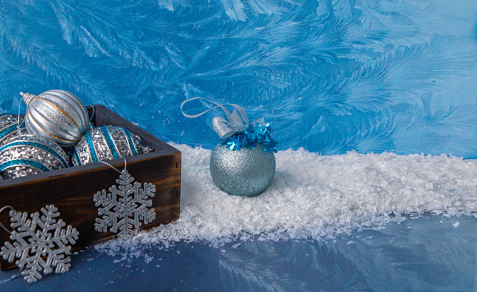 Christmas mood, holiday atmosphere. Blue and silver Christmas balls in a wooden box on the snow. Christmas card.