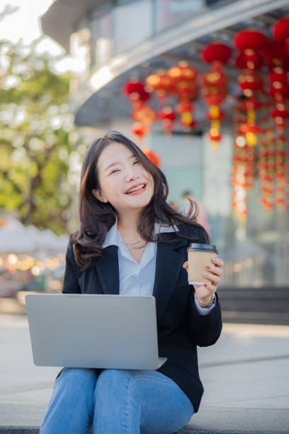 istock Asian businesswoman using the phone while having coffee while traveling is the new normal in the city, woman working with laptop outdoors. 1444334609