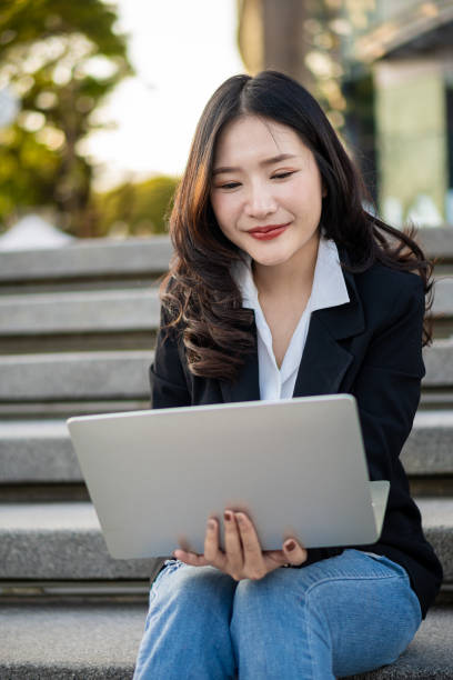istock Asian businesswoman using the phone while having coffee while traveling is the new normal in the city, woman working with laptop outdoors. 1444334768
