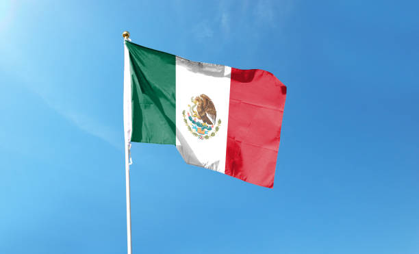 istock Mexican flag in cloudy sky. Waving in the sky 1444338989