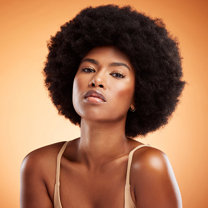 Skincare, portrait and black woman with face makeup against an orange studio background. Young, african and beauty girl model with glow from cosmetics, healthy body and care for skin with dermatology