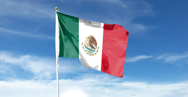 istock Mexican flag in cloudy sky. Waving in the sky 1444339576