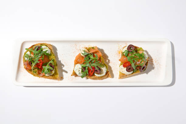 istock Aesthetic composition with salmon bruschetta on white backgroundover white wall. Italian bruschetta with salmon, avocado, cheese and olives on fine dining in summer. Elegant menu concept. 1444342131