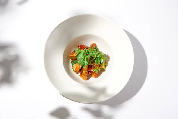 istock Crispy eggplant in chinese style on white plate. Crispy eggplant salad on summer menu. Asian appetizer - roasted aubergine with coriander leaves. Vegan food. Aesthetic veggie menu. 1444342149