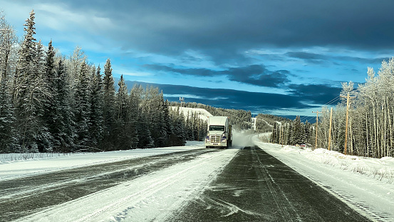 This truck is traveling on a snow covered highway in the interior of Alaska in winter.