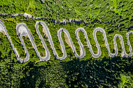 Aerial view of winding road with many hairpin turns in mountain forest