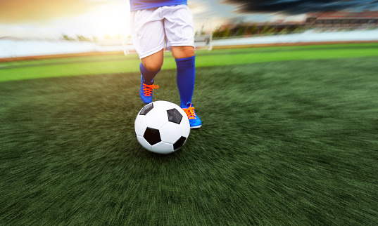 Low section of young boy feet kicking a soccer ball